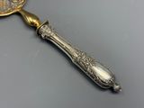 une cuillère en argent avec un manche en or posée sur une table