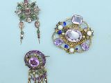 three pieces of jewelry on a table with a blue background