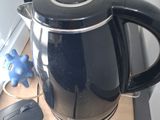 a black kettle that is on a desk next to a computer mouse