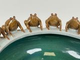 a group of frogs sitting on top of a green bowl