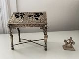 a small silver table with a figurine next to it
