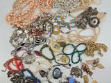 a pile of assorted necklaces and bracelets on a white surface