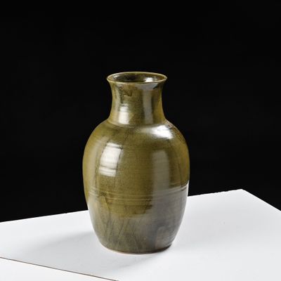 un grand vase vert posé sur une table blanche
