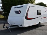 un petit camping-car blanc garé sur un parking