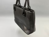 black leather handbag on a white surface with a white background