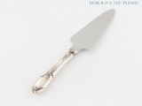 a silver cake knife with a silver handle on a white surface