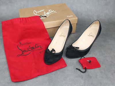 une paire de chaussures noires pour femme dans un sac rouge, à côté d'une paire de chaussures rouges