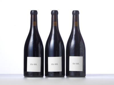 three bottles of red wine are lined up on a table