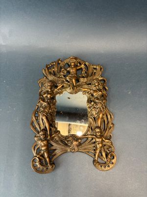 a gold mirror on the wall with a statue in it
