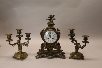 a clock and three candlesticks sitting on a table