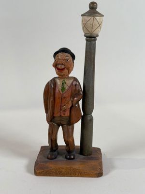 a wooden statue of a man standing next to a lamp post