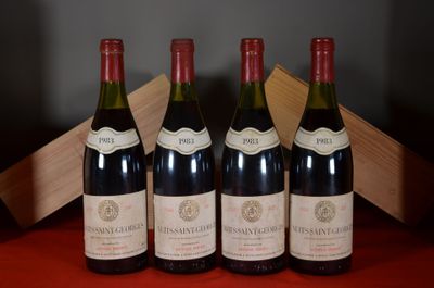 four bottles of wine are lined up on a red table