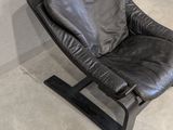 a black leather chair sitting in a corner of a room