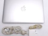 an apple laptop computer sitting on top of a white table next to a charger
