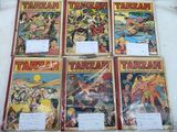 Plusieurs bandes dessinées sont alignées sur une table, à côté d'une pancarte