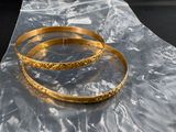 two gold bracelets sitting on a plastic bag