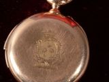 a gold pocket watch in a red case with a tag on it