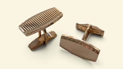 pair of gold tone cufflinks with a comb on top of them