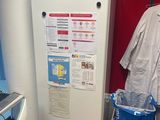 a white refrigerator in the corner of a room with clothes hanging on the wall