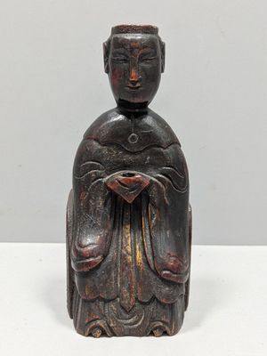 une vieille statue en bois représentant une femme tenant une fleur