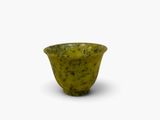 un petit bol vert posé sur une surface blanche