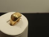 une bague en or posée sur un récipient blanc