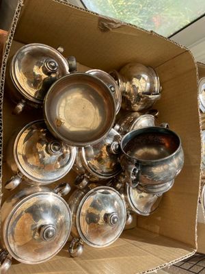 de nombreuses casseroles et poêles dans une boîte posée par terre