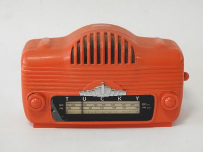 une radio orange posée sur une table près d'un mur blanc