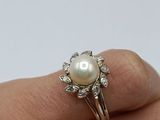 an image of a woman ' s hand holding a pearl and diamond ring