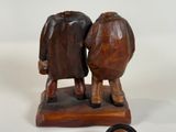 two figurines of two people standing on a wooden base