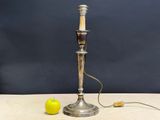 a silver lamp that is on a table with a green apple