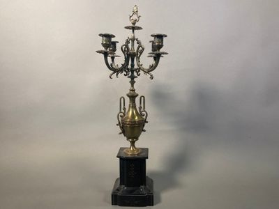 an antique brass candelab with four candles on a marble base