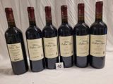 six bottles of red wine are lined up on a table