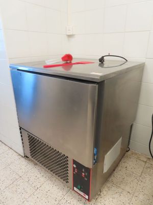a small stainless steel freezer with a red handle on it