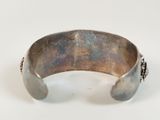 silver cuff bracelet with chain detail on a white background
