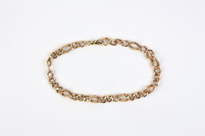 a gold chain bracelet with an oval link on a white background