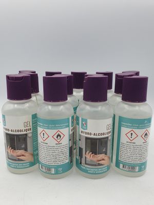 quatre flacons de gel hydroalcoolique posés sur une surface blanche