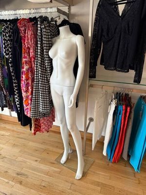 a mannequin in front of a rack of clothes