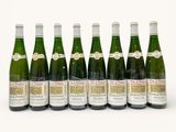six bottles of wine are lined up in a row on a white surface