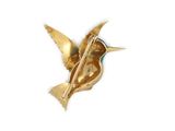 a gold bird brooch on a white background