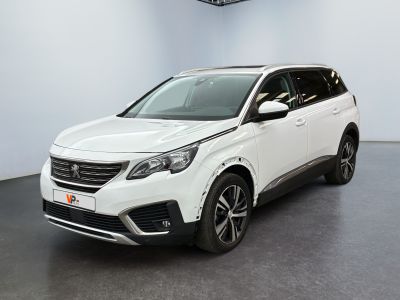 La voiture blanche est garée dans une grande pièce équipée d'un ventilateur de plafond.