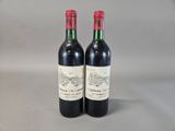 two bottles of red wine sitting next to each other on a table