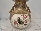 un vase sur lequel est peint un oiseau, posé sur une table