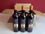 trois bouteilles de vin rouge dans un carton sur une table