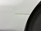 a close up of a white car with scratches on the side of it