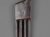a metal comb with a wooden handle on a gray surface