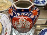 de nombreuses assiettes et vases posés sur une table en verre, avec un homme en arrière-plan