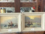 deux tableaux représentant des bateaux, posés sur une table devant un mur de briques