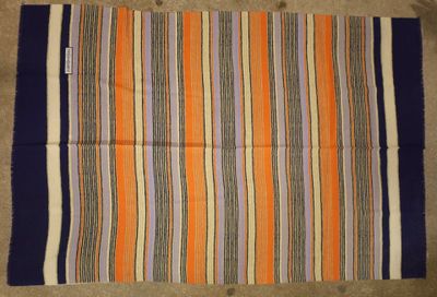an orange, blue and white striped rug on the floor