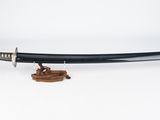 un sabre de samouraï noir avec une poignée en bois sur fond blanc